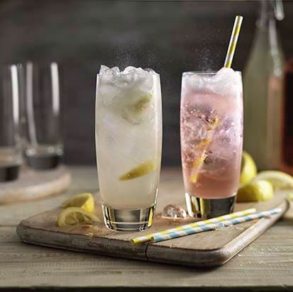 Two glasses of carbonated drinks, cloudy lemonade and pink lemonade with ice