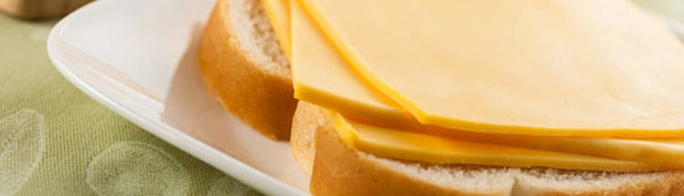 Close-up of sliced cheese layered on bread, highlighting texture and smoothness