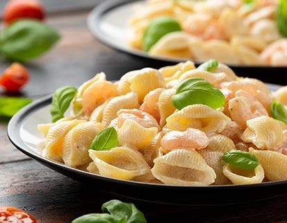 Bowl of creamy pasta with leaved herbs, highlighting savory ready meal solutions