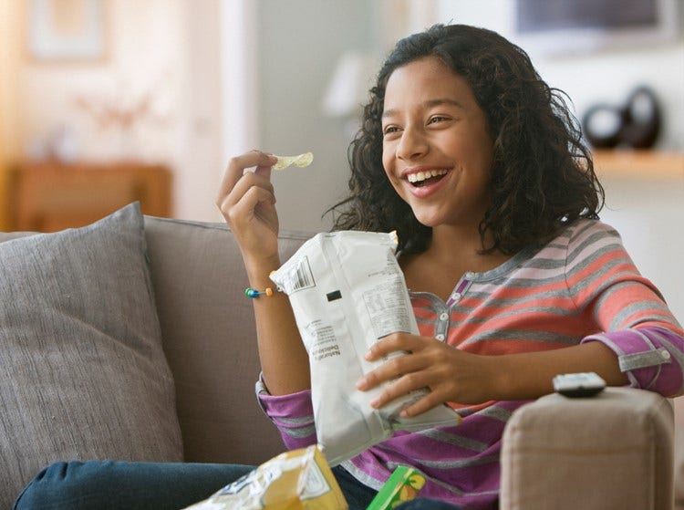 Smiling woman eating popcorn from a bowl, highlighting snacking innovation insights