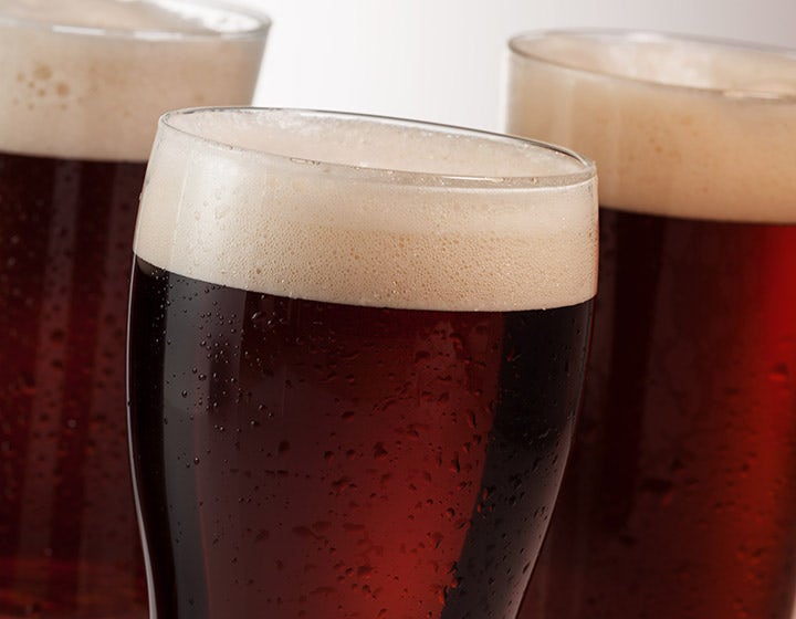 Glass of dark beer with foam, representing brewing and alcoholic beverage solutions