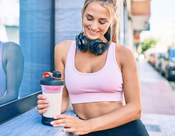 Athletic woman drinking a protein shake outdoors, promoting protein and texture benefits in beverages
