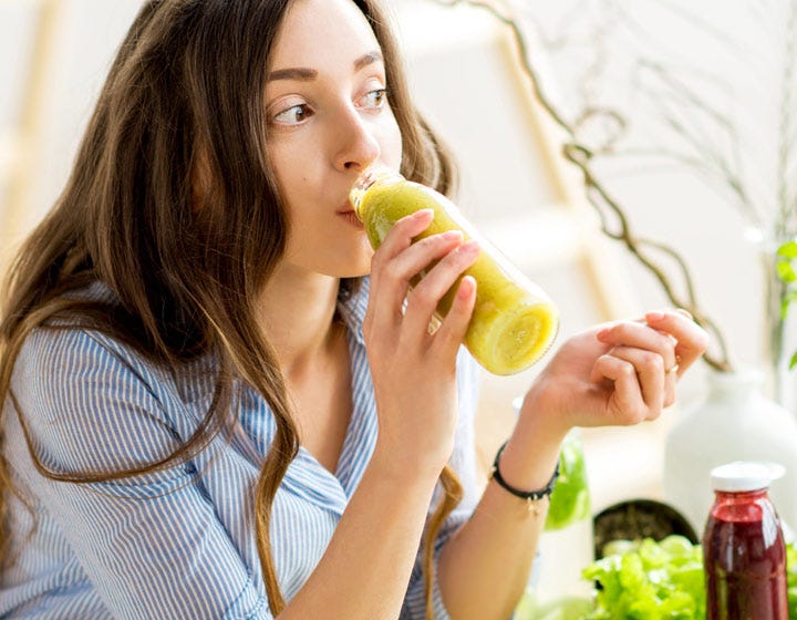 Woman drinking juice from a glass bottle, emphasizing new beverage product development
