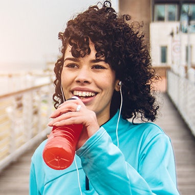 Woman drinking a red drink while exercising outdoors, highlighting sports nutrition opportunities